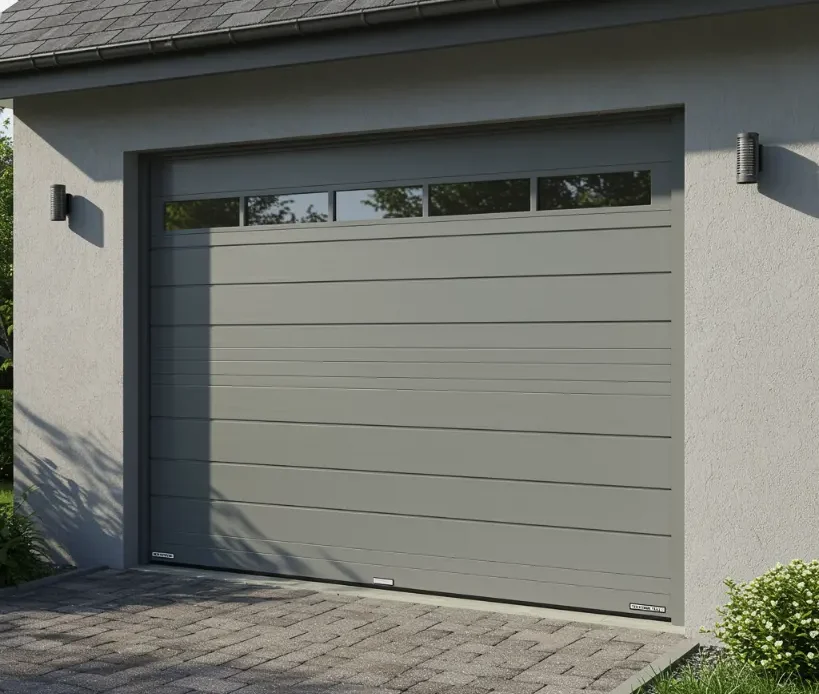 Modern gray bi-fold garage door with horizontal panels and upper windows on a residential driveway.