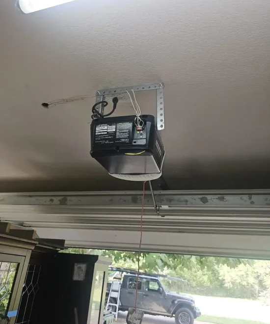 Garage door opener mounted on a garage ceiling, open door with a truck parked outside