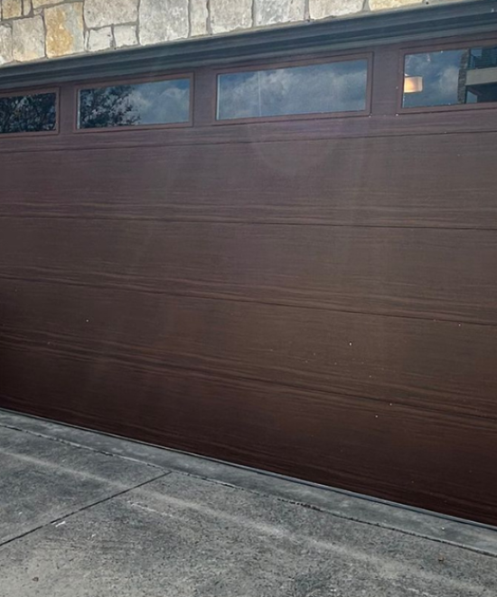 Wood-look sectional garage door on a stone-front home
