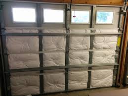 White insulation batts fitted into the panels of a garage door with a row of windows