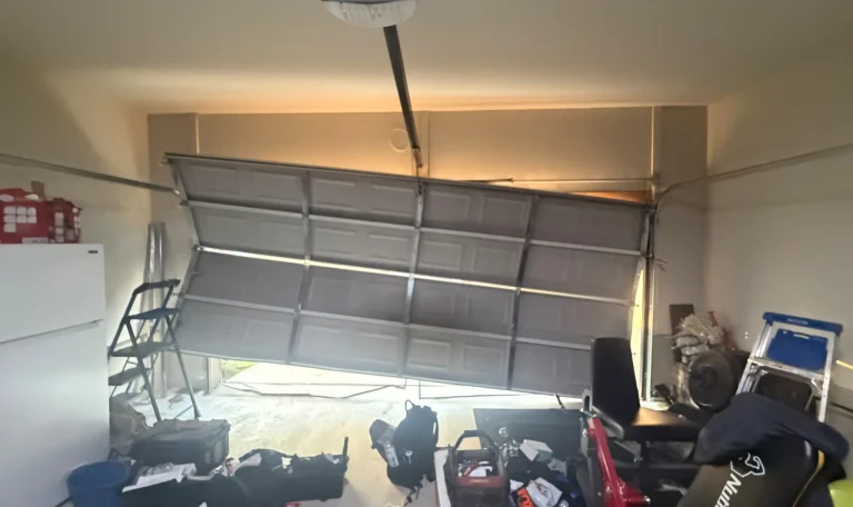 Partially open gray sectional garage door beneath a ceiling-mounted opener, with tools and equipment on the floor.