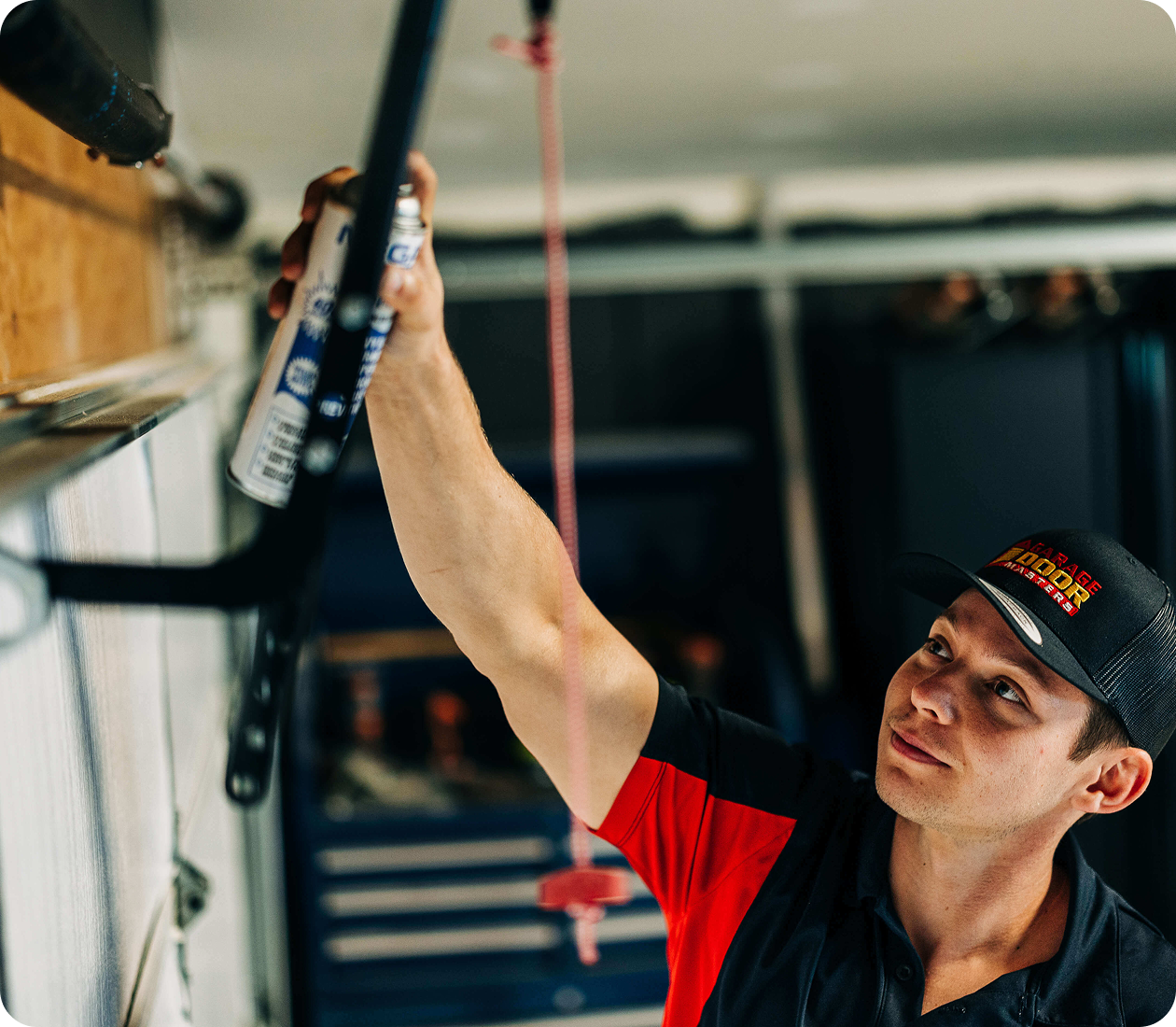 Technician lubricating a garage door track during a maintenance visit