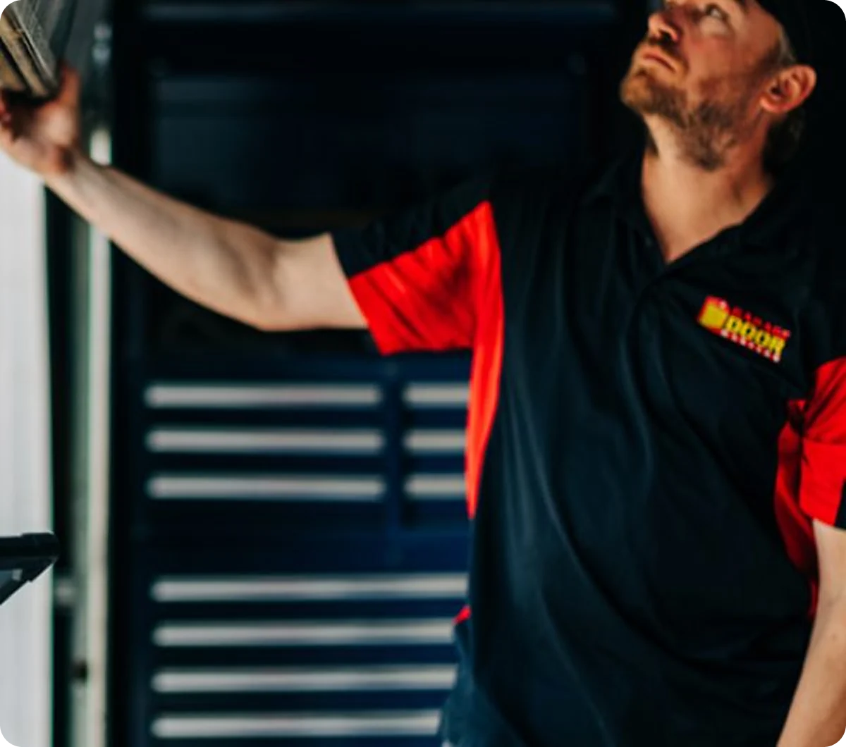 Technician reaching up to service a garage door