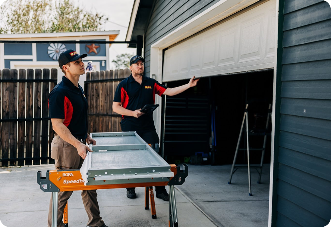 Technicians preparing a garage door section outside a home